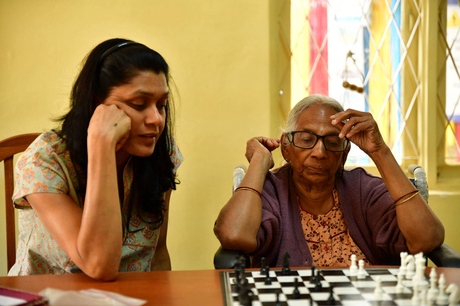 An elderly member deep in thought while engaging in a game of chess with our staff